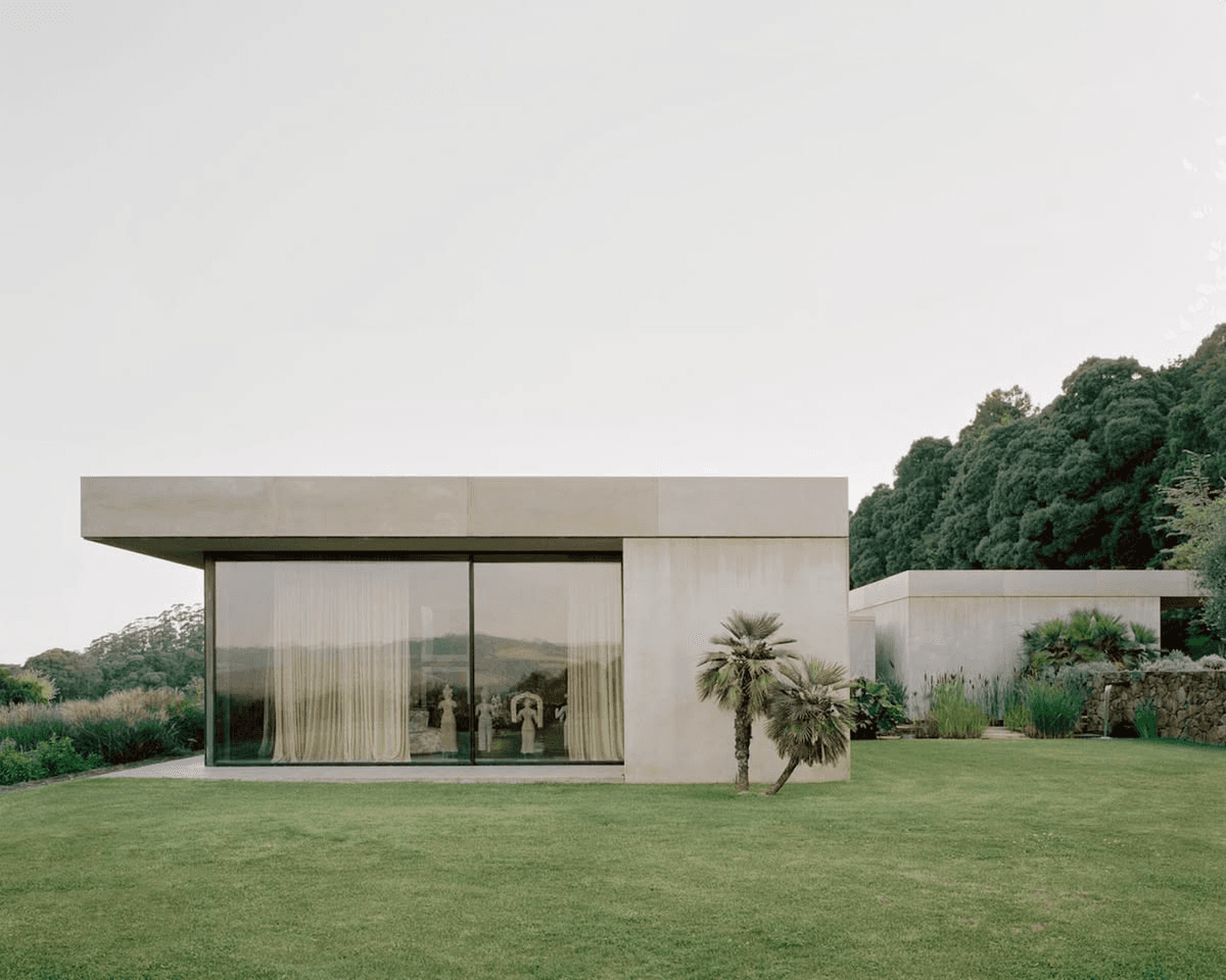A low concrete house with floor-to-ceiling windows on a green lawn